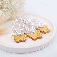 Gold butterfly-shaped party favors on a pearl bead mini rosaries with a white background