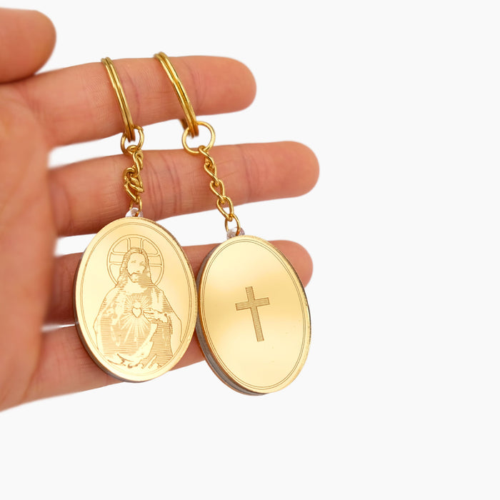 Gold Jesus Christ pendants with religious designs held in a hand against a white background