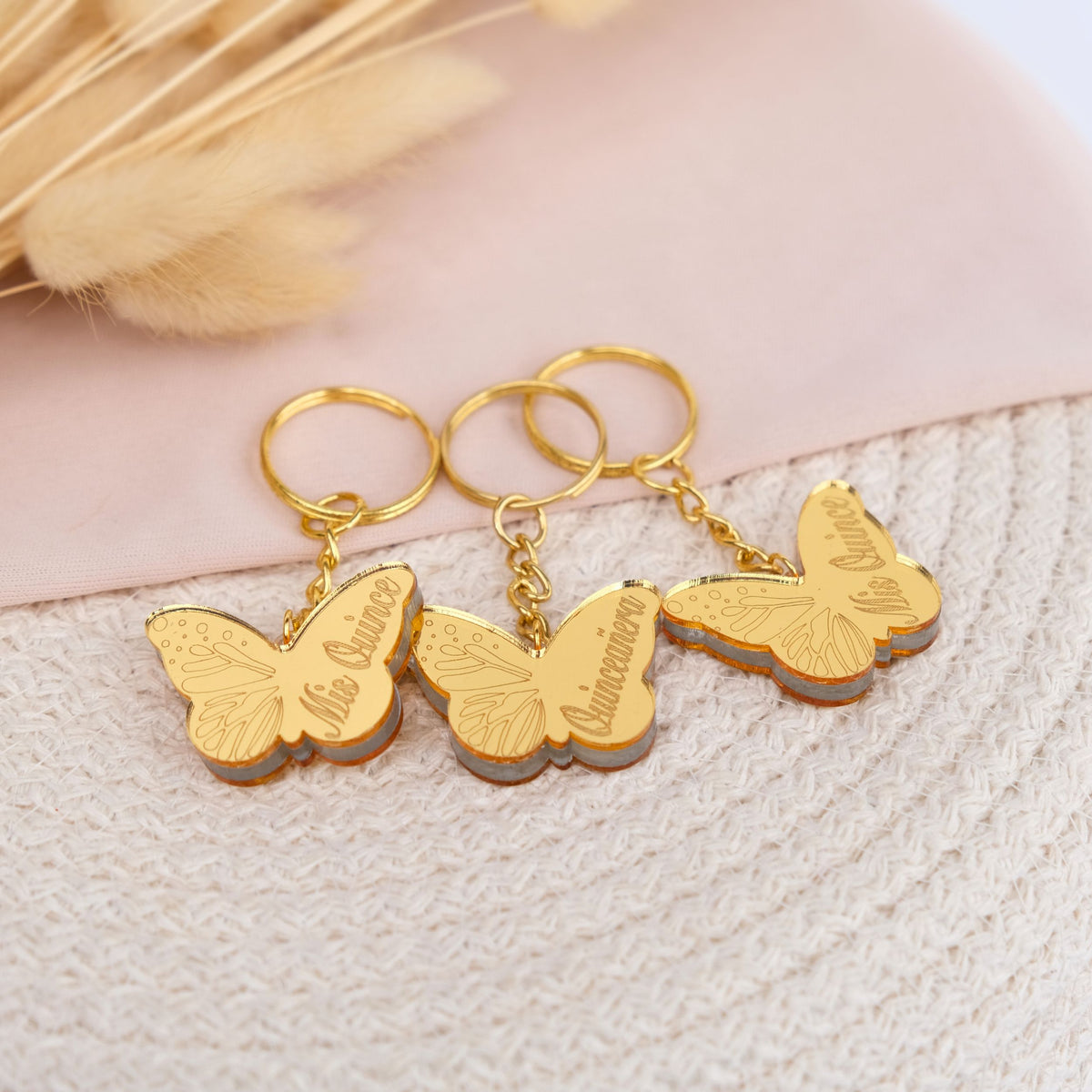 Gold butterfly keychains with engraved text on a textured surface. party favors bulk