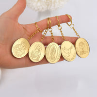 Gold medallion pendants on chains held by a hand against a white background baptism favors