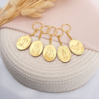 Set of gold keychains with religious designs on a textured surface.