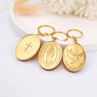 Three gold keychains with religious symbols on a white surface