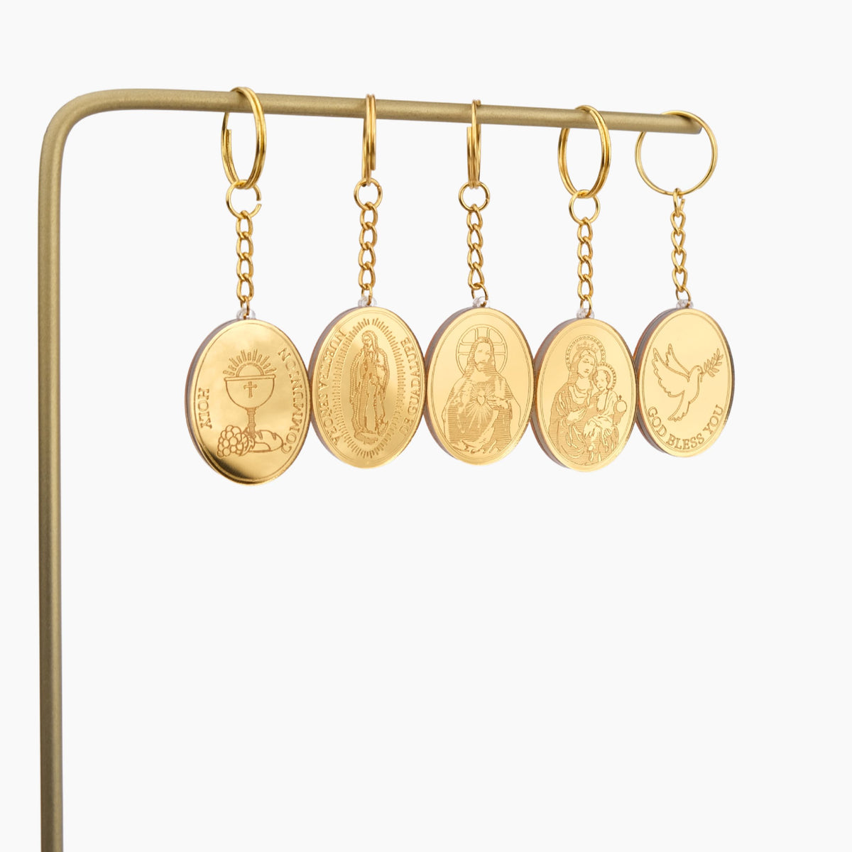 Gold oval pendant keychains on a gold stand against a white background