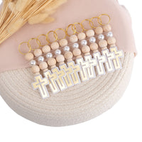 Keychains with wooden beads and cross pendants on a textured surface