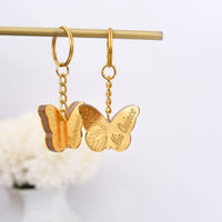 Gold butterfly keychain favors on a white background