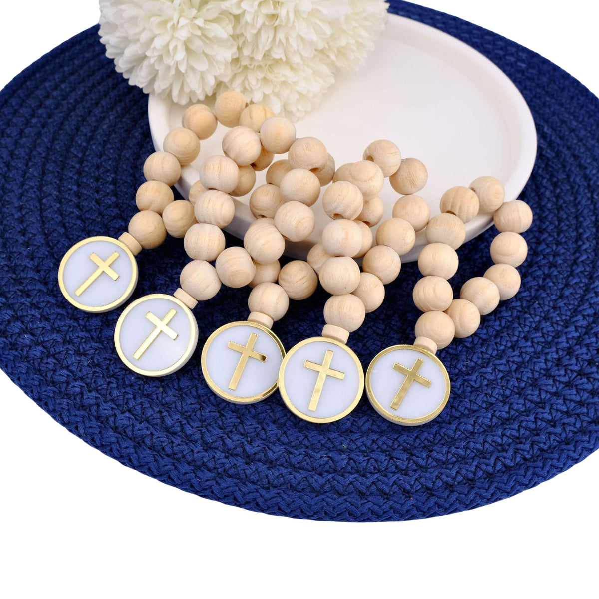 Wooden mini rosary beads with cross charms on a blue textured surface