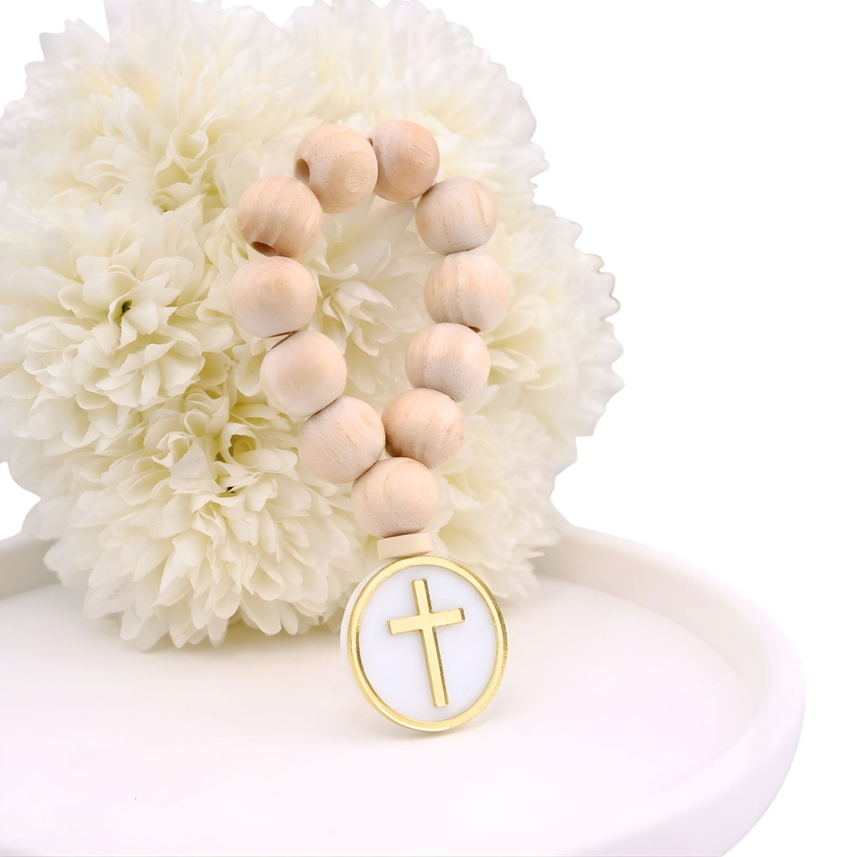 Wooden beaded bracelet with a gold cross charm on a white flower background