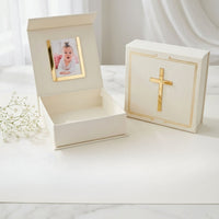 White keepsake box with gold accents featuring a cross design on a white surface.