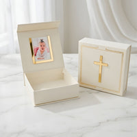 Decorative box with gold cross design and photo frame on a white marble surface