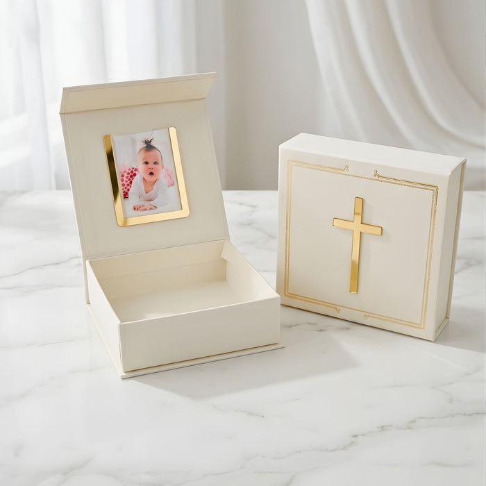 Decorative box with gold cross design and photo frame on a white marble surface