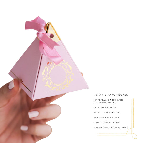 Pink pyramid favor box with gold foil detail and pink ribbon held by a hand on a white background.