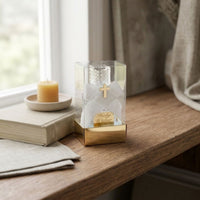 Clear acetate box with gold base labeled 'Holy Water'  glass bottle on a wooden surface with books and a candle.