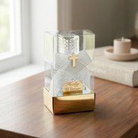 Holy water bottle with decorated box and gold base and cross on a wooden surface