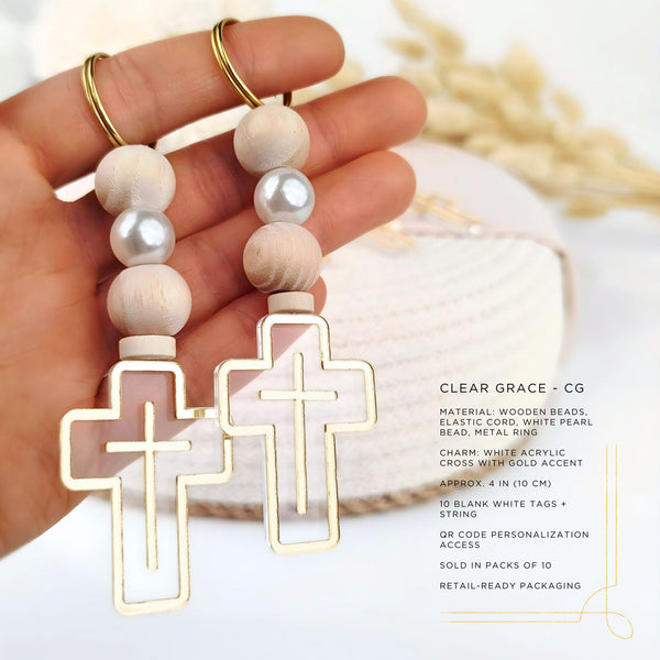 Hand holding a pair of cross-shaped keychains with wooden beads and gold accents.