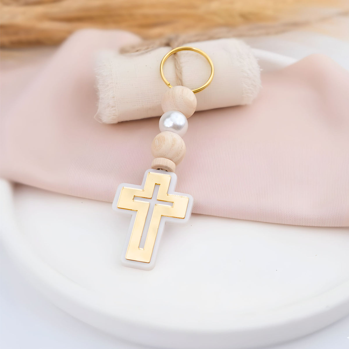 Keychain with cross pendant and wooden beads on a soft fabric background