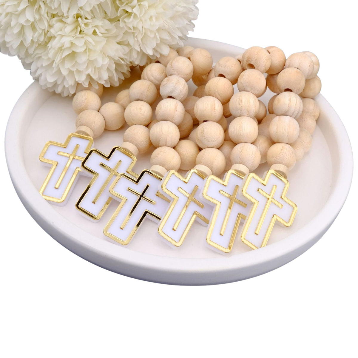 Wooden beaded mini rodsary with cross pendants on a white dish with flowers in the background