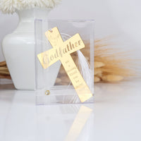 Gold cross with 'Godfather' engraving in a clear packaging on a light background