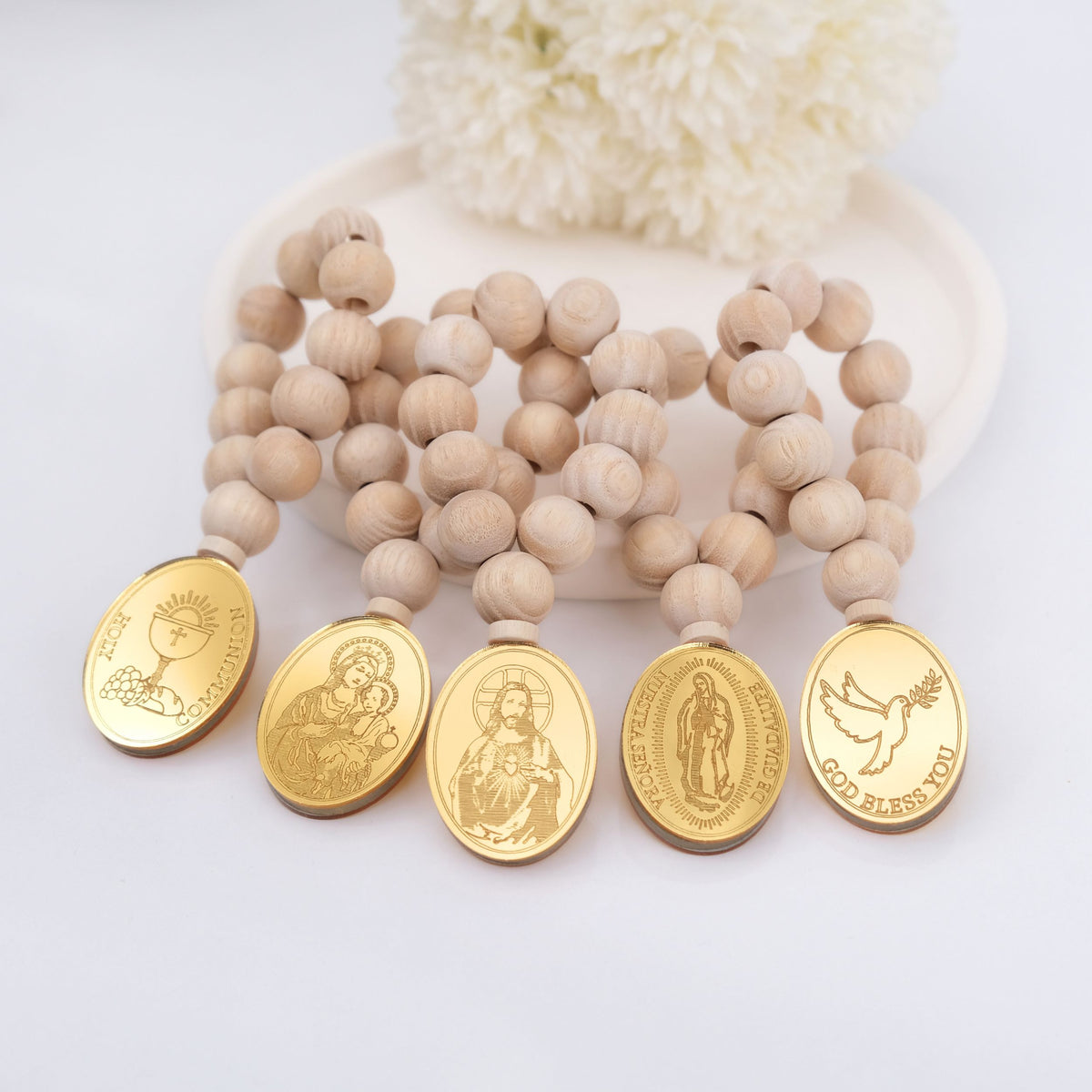 Wooden beaded mini rosaries with gold religious medals on a white background