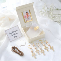 Baby shower gift set with pacifier clip, photo frame, and card on a white fabric background