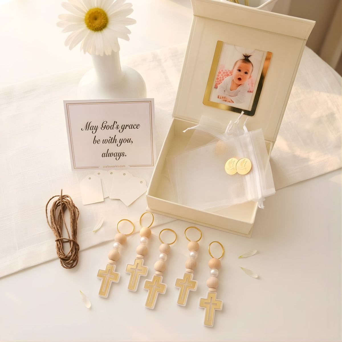 Decorative keychains with crosses, a card, and a baby photo in a box on a light surface.