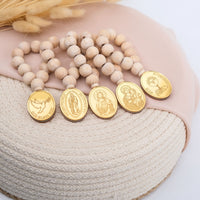 Mini Rosaries with wooden beads and gold religious pendants on a textured surface