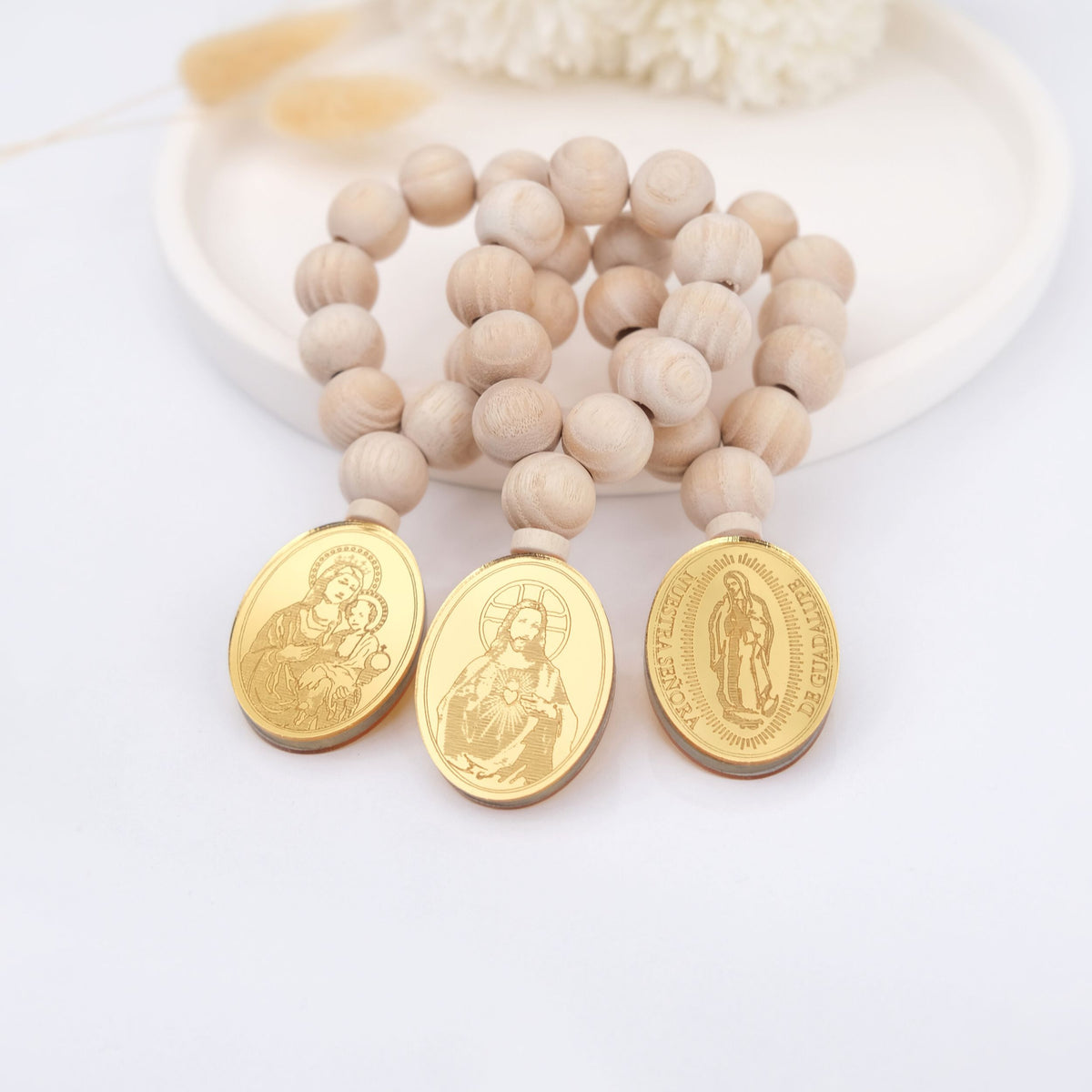 Mini rosary catholic favors with wooden beads and gold religious medallions on a white background