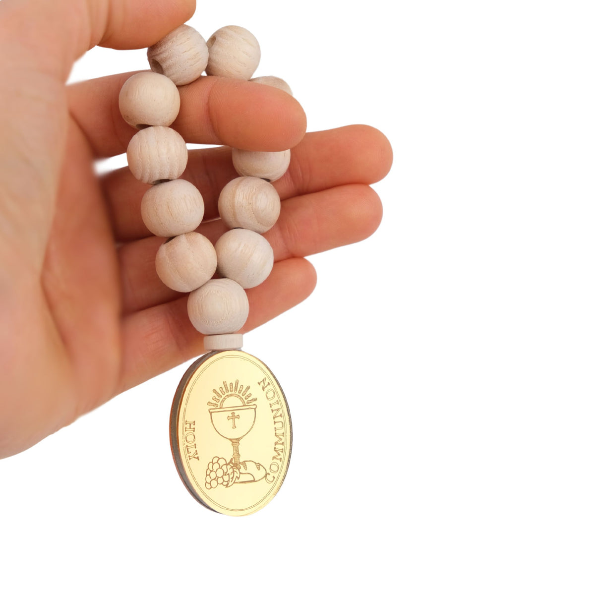 Hand holding a wooden rosary first communion favors with a gold pendant on a white background