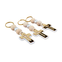Three cross-shaped keychains with wooden beads on a white background