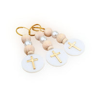Pair of keychains with wooden beads and gold crosses on a white background, event favors