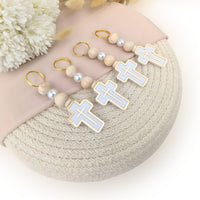 keychain baptism favors with cross designs on a textured surface with flowers in the background