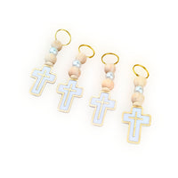 Set of four cross-shaped charms on wooden beads with gold loops against a white background