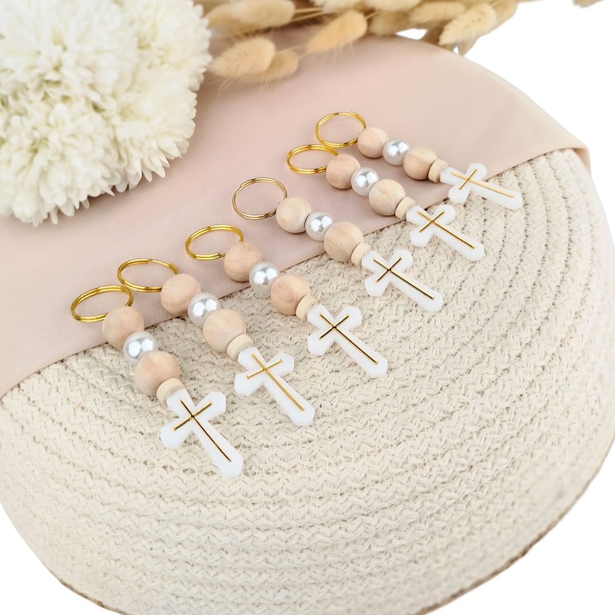 Set of wooden beaded keychains with cross designs on a textured surface.