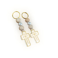 Pair of baptism favor keychains with gold loops, wooden beads, and cross designs on a white background