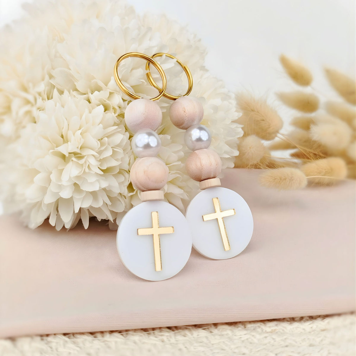 Pair of baptism keychains with cross designs on a soft background