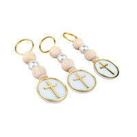 Two keychains with gold crosses on white beads against a white background