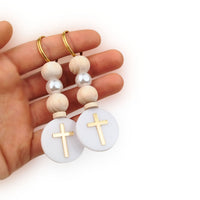Hand holding two keychains with wooden beads and gold crosses on a white background, first communion gift