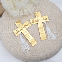 Two gold crosses with 'Godmother' and 'Godfather' inscriptions on a textured surface.