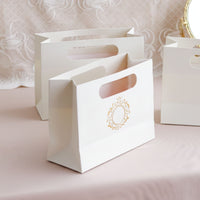 White paper bags with gold details on a pink surface