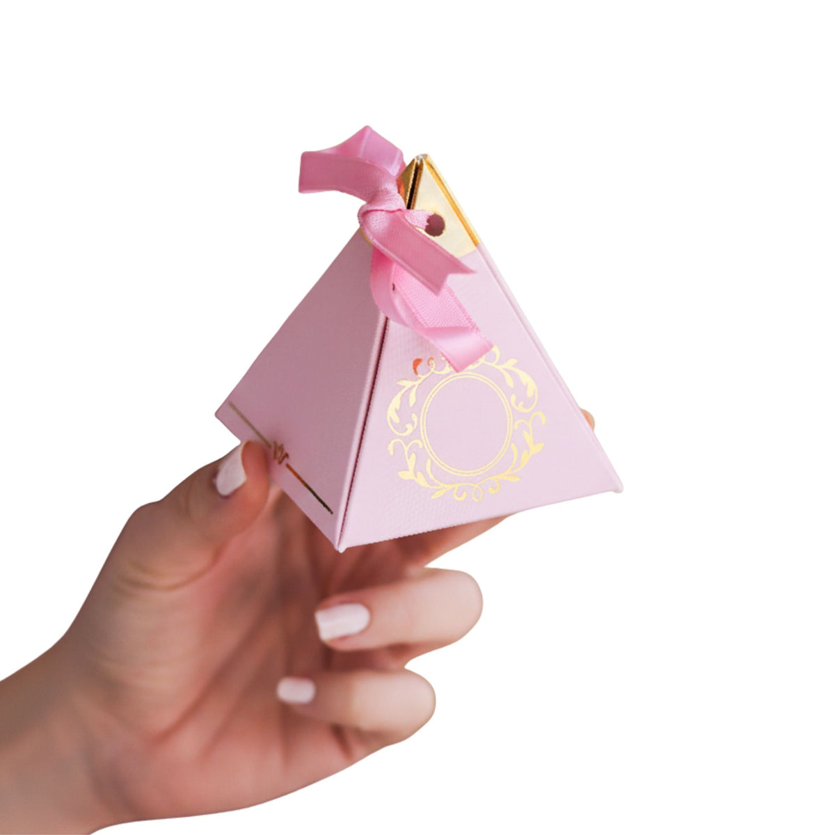 Hand holding a pink pyramid-shaped gift box with gold accents on a white background