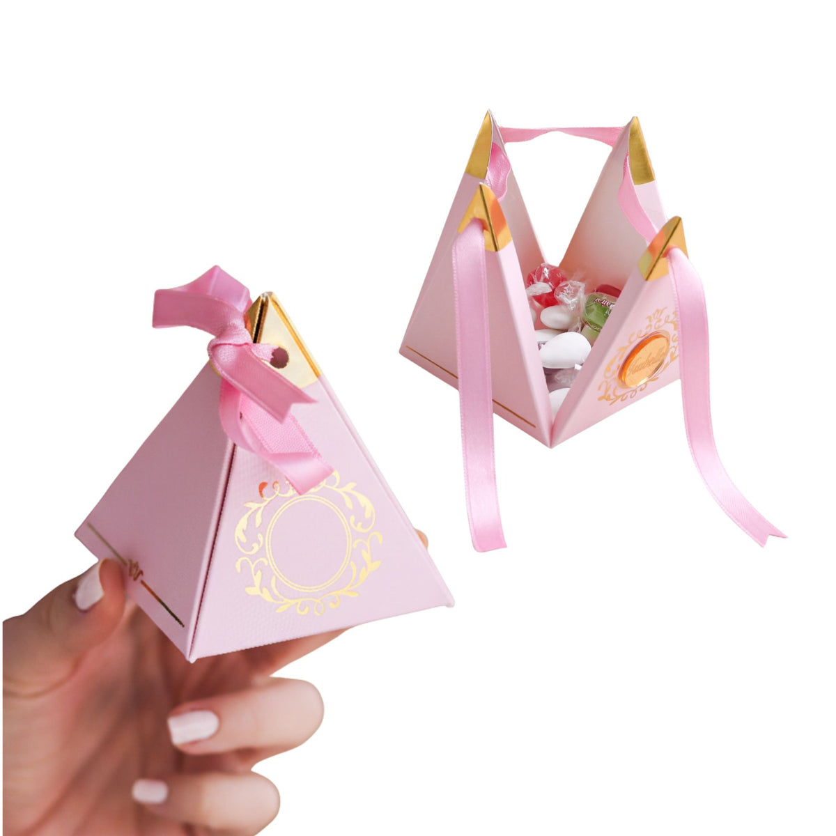 Pink pyramid-shaped gift box with a ribbon held by a hand on a white background
