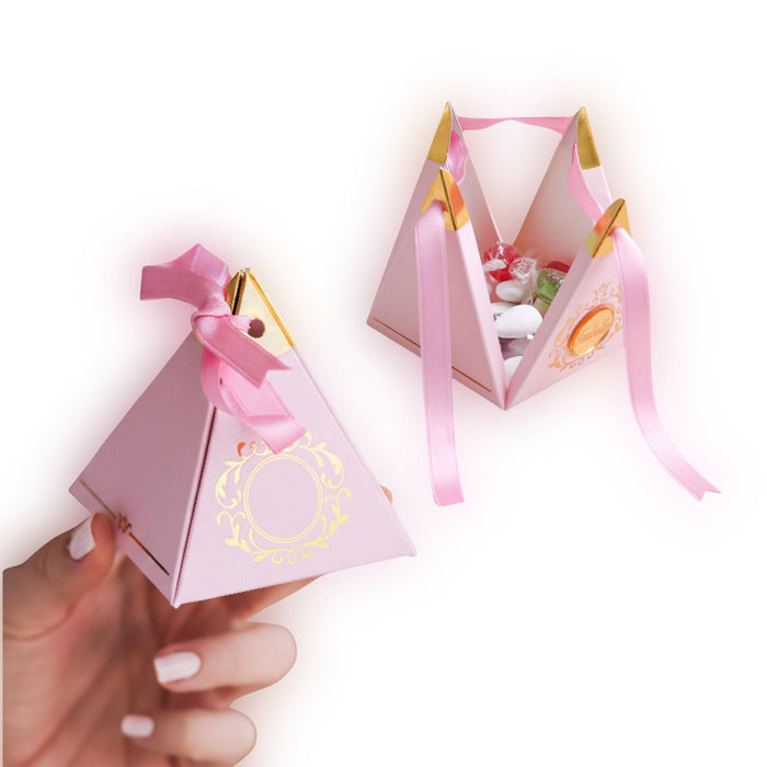Pink pyramid-shaped gift box with a ribbon held by a hand on a white background