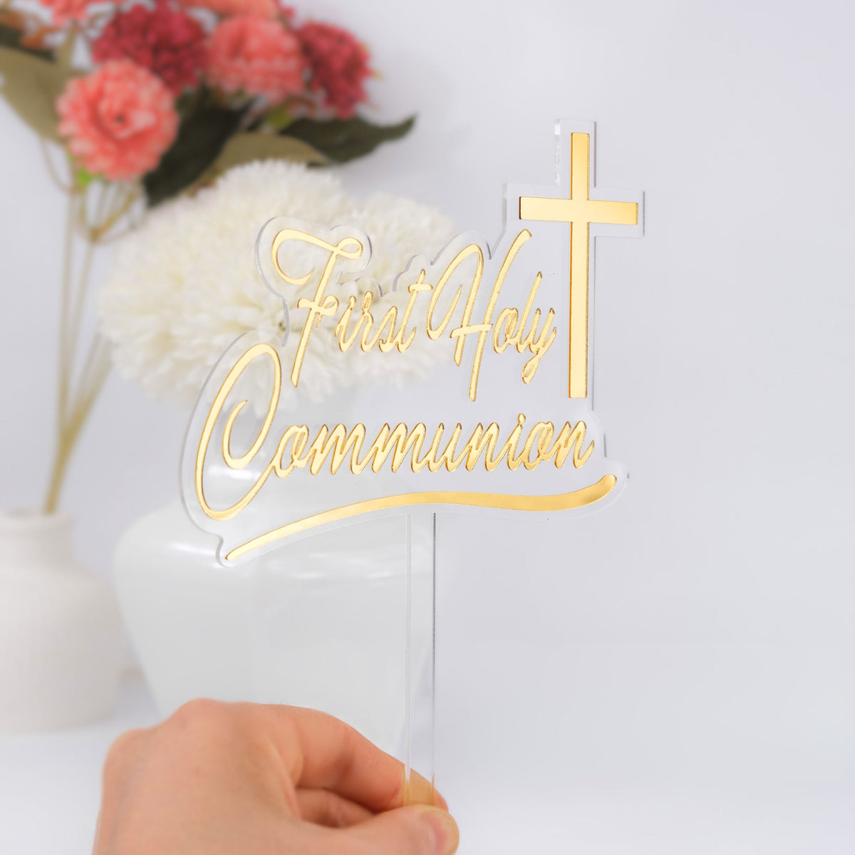 Gold 'First Holy Communion' sign with a cross on a white background