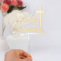 Gold 'First Holy Communion' cake topper held by a hand with flowers in the background