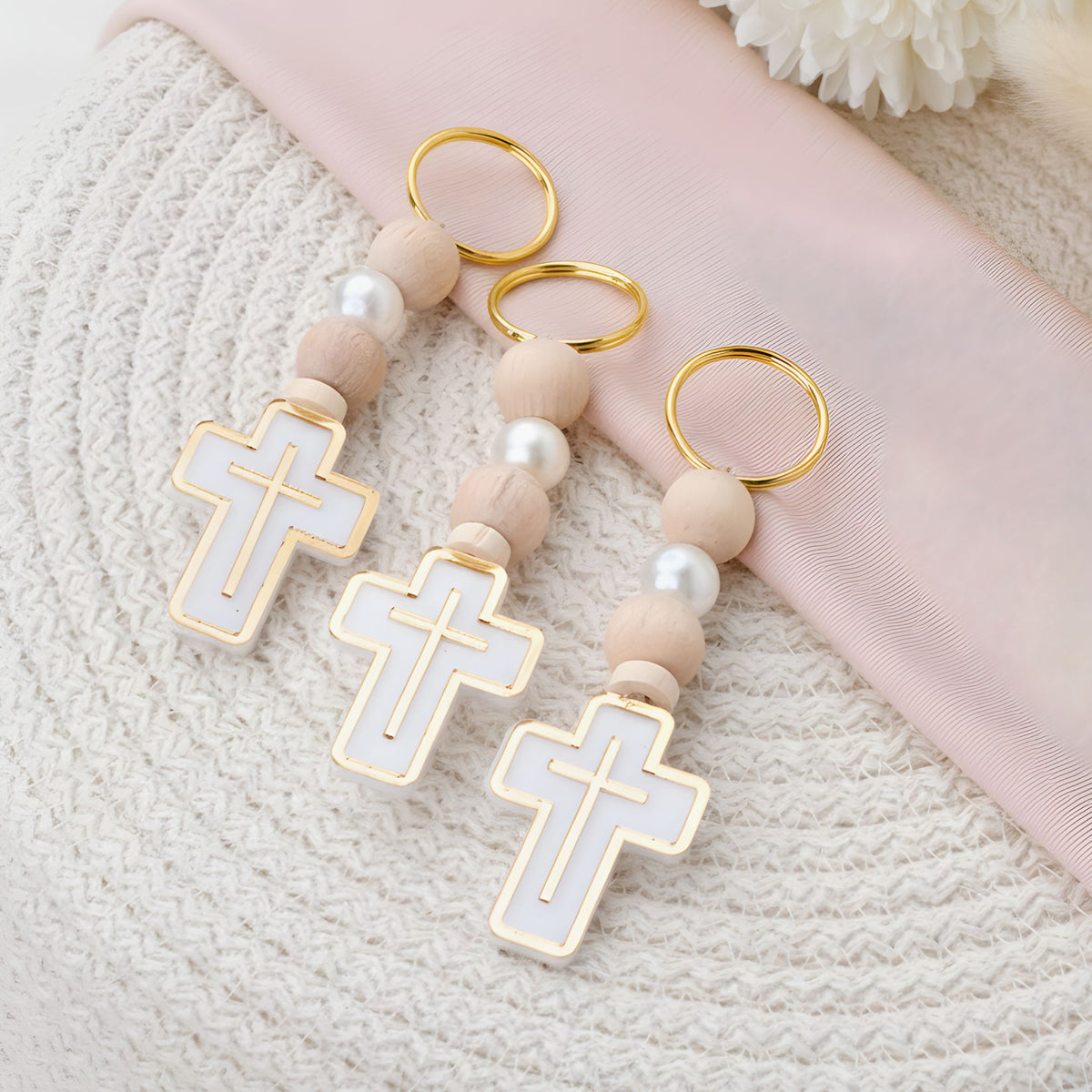 Decorative keychain with cross designs and pearl-like beads on a textured surface.