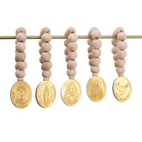 Set of five wooden beaded mini rosaries with gold religious medallions on a white background