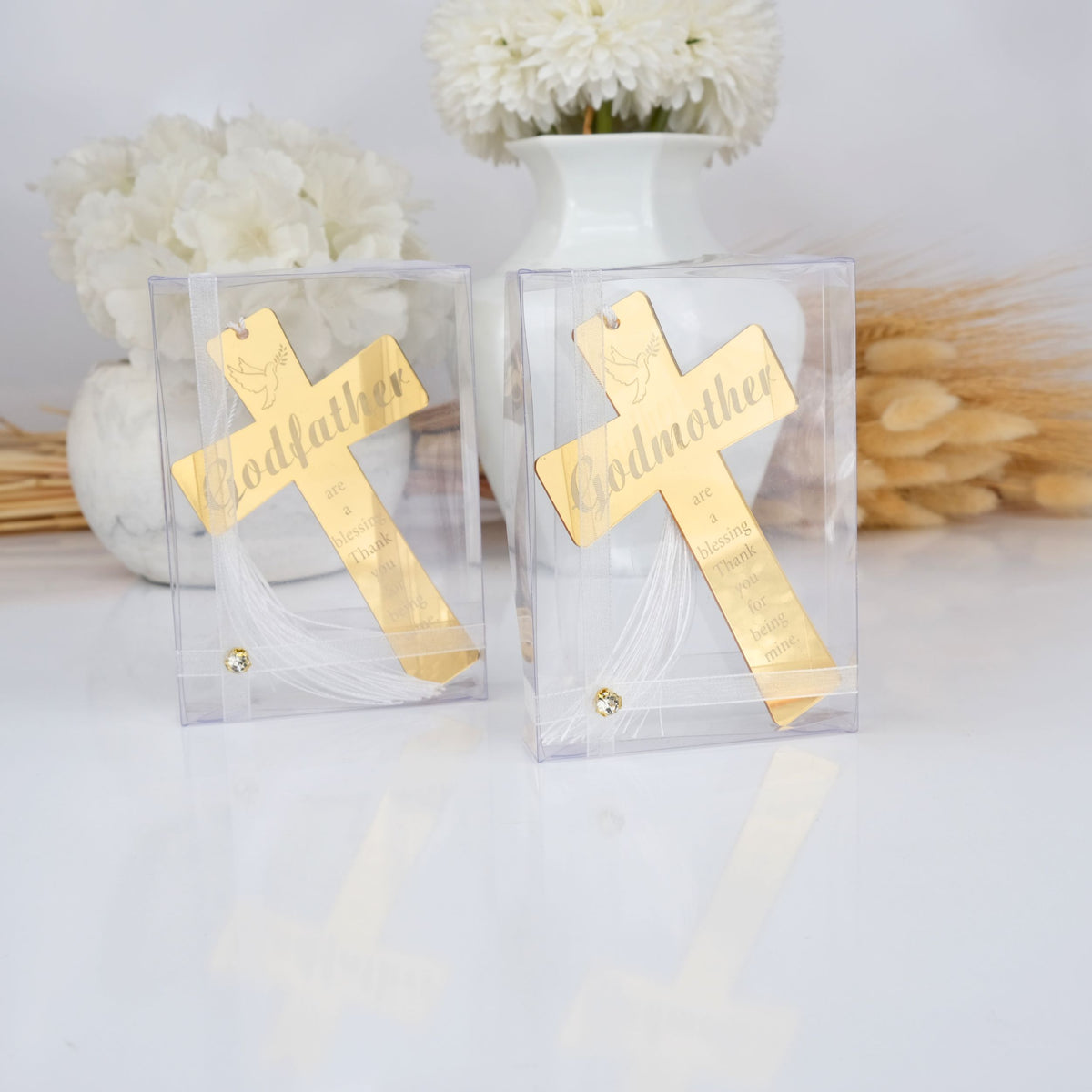 Two gold crosses labeled 'Godfather' and 'Godmother' in clear boxes with white flowers and wheat in the background.
