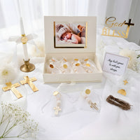 Collection of gold religious baptism items including crosses and a photo frame on a white surface with 'God Bless' cake topper.