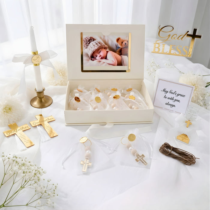 Collection of gold religious baptism items including crosses and a photo frame on a white surface with 'God Bless' cake topper.