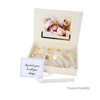 Gift box with baby photo, gold accents, and a card inside on a white background