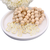 Wooden beaded rosary favors on a white plate with white flowers in the background